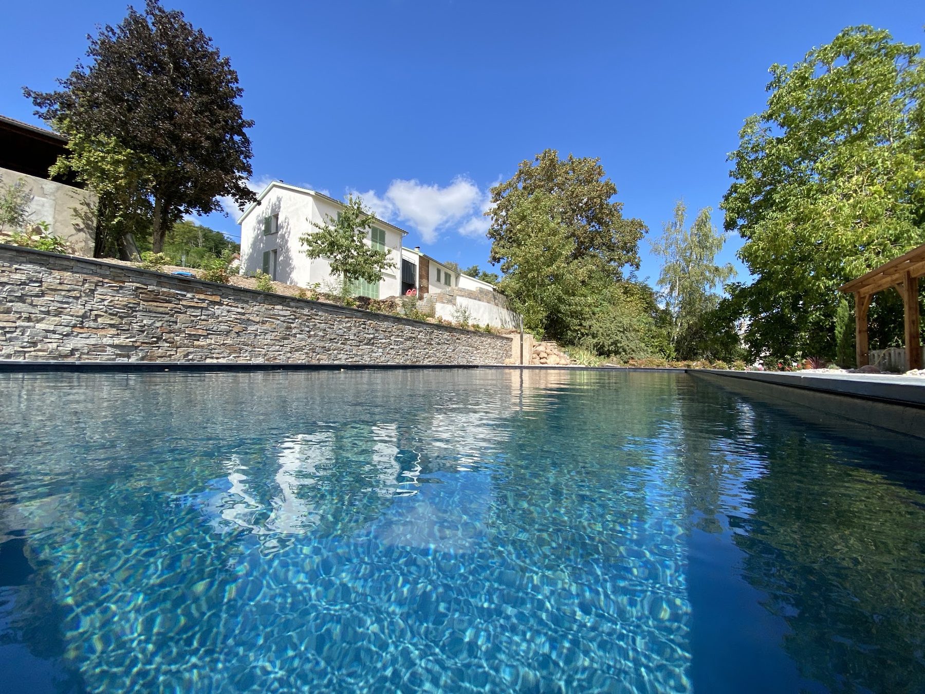 Bassin, mur de soutènement en pierre et jardin en terrasses sous le ciel bleu