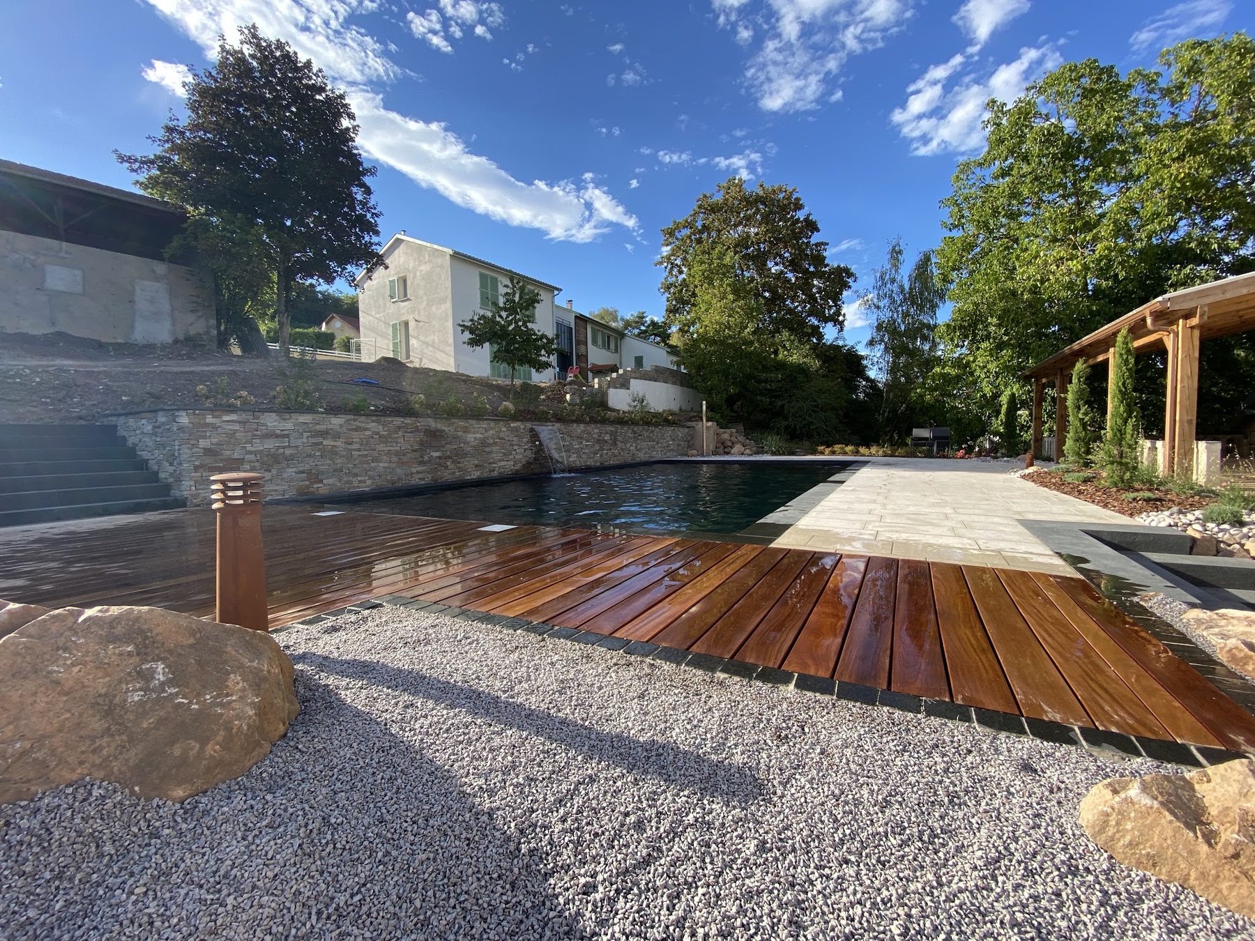 Terrasse en bois, gravier et rochers au bord d'un bassin